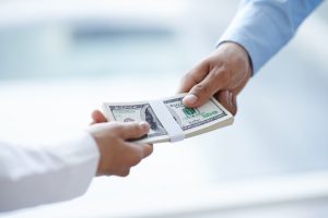 Hands of businessman giving money to his partner